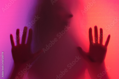 the girl's arms and torso are illuminated through the fabric from the other side