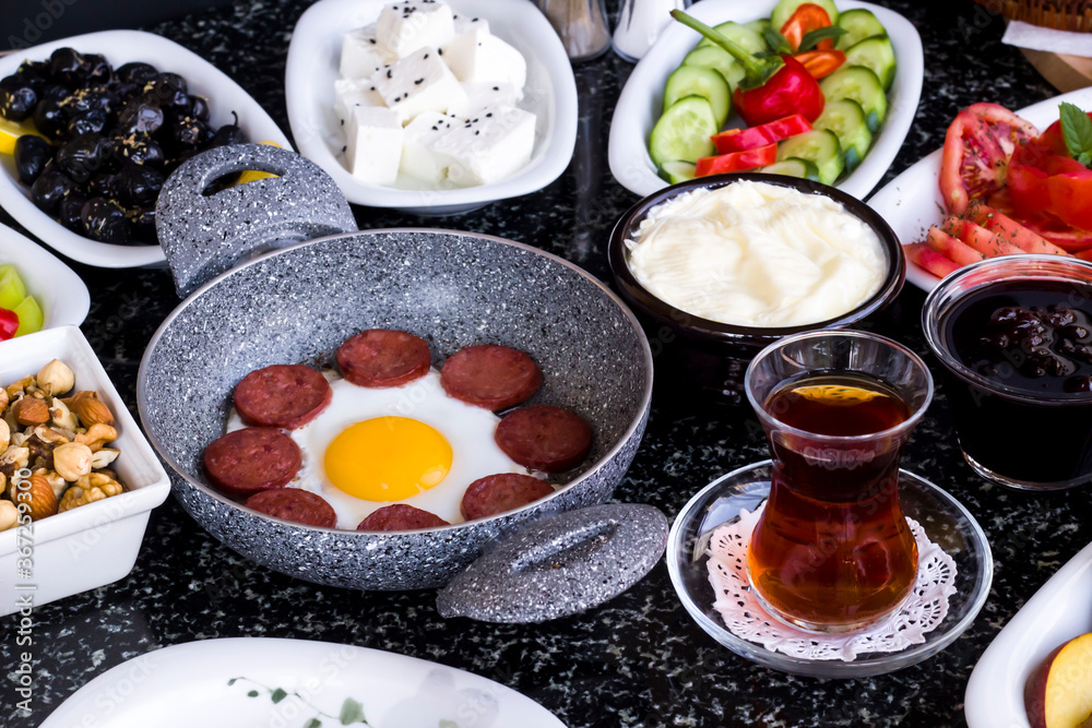 Traditional Turkish Breakfast with sausage egg pan on granite marble table.Close and large view Traditional Turkish Breakfast with sausage egg pan on granite marble table.Close and large view