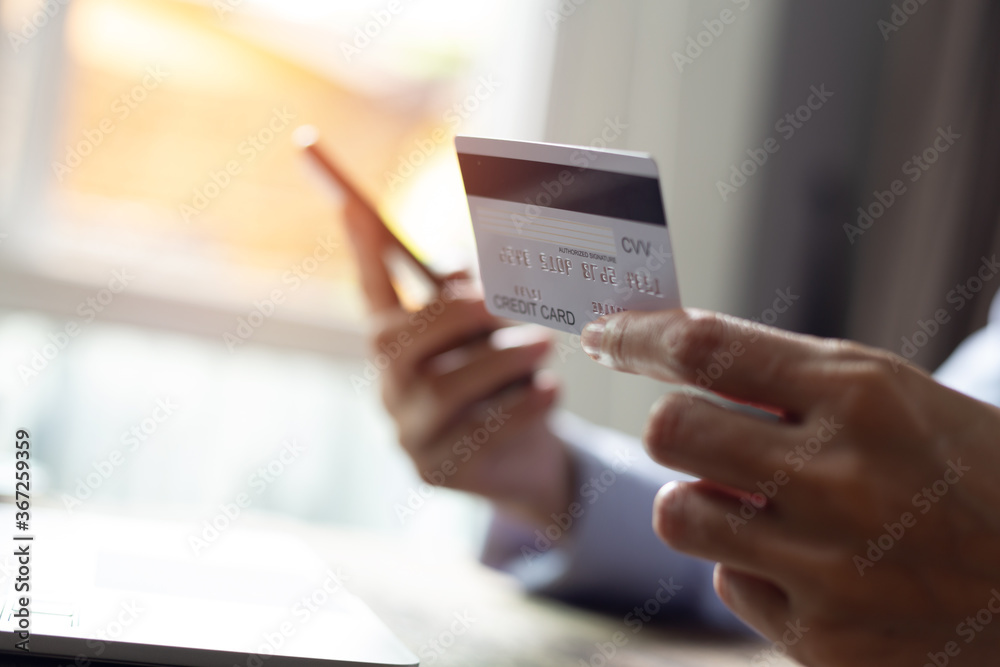Woman hand holding credit card and using smart phone with laptop computer Online shopping concept Woman hand holding credit card and using smart phone with laptop computer Online shopping concept