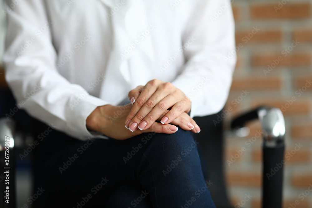 Obraz premium Woman in white blouse sit on chair with her hands folded together on her knees. Professional psychologist conduct session. Treatment of mental illness. Psychological conversation for treatment of