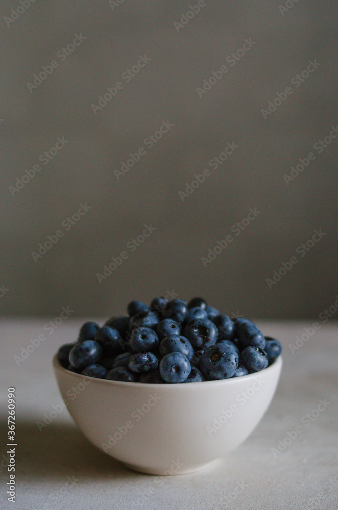 Fresh blueberry in ivory bowl on dark grey background. Freshness of sweet ripe berries Fresh blueberry in ivory bowl on dark grey background. Freshness of sweet ripe berries