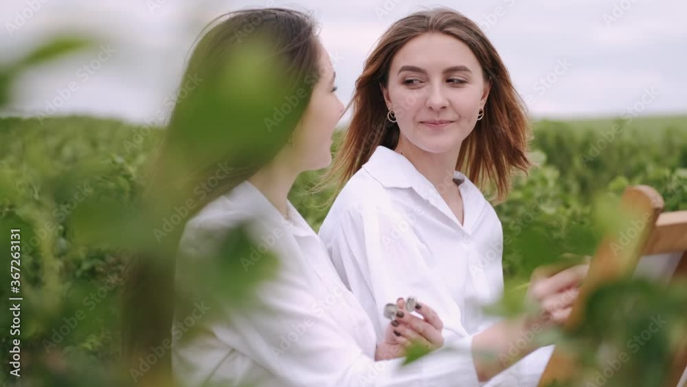 Women in a summer field. Cute lady drawing. Girl in a white shirt.