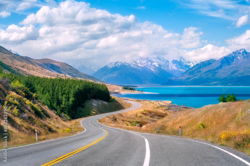 The winding road along the shore of Lake Pukaki, a glacial alpine lake in Mount Cook NP in New Zealand's South Island, set in a glacier-carved valley surrounded by snow-capped mountain peaks. The winding road along the shore of Lake Pukaki, a glacial alpine lake in Mount Cook NP in New Zealand's South Island, set in a glacier-carved valley surrounded by snow-capped mountain peaks.