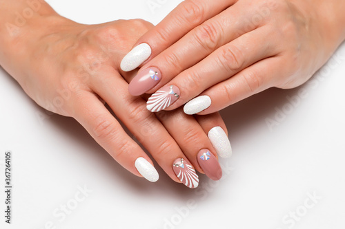 Wedding summer manicure. Drawn shell with crystals. White sequins. Delicate beige manicure on long oval nails on a white background. Summer manicure.