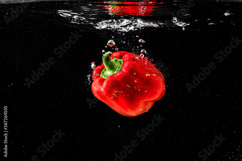 red Pepper splashing into water on black background
