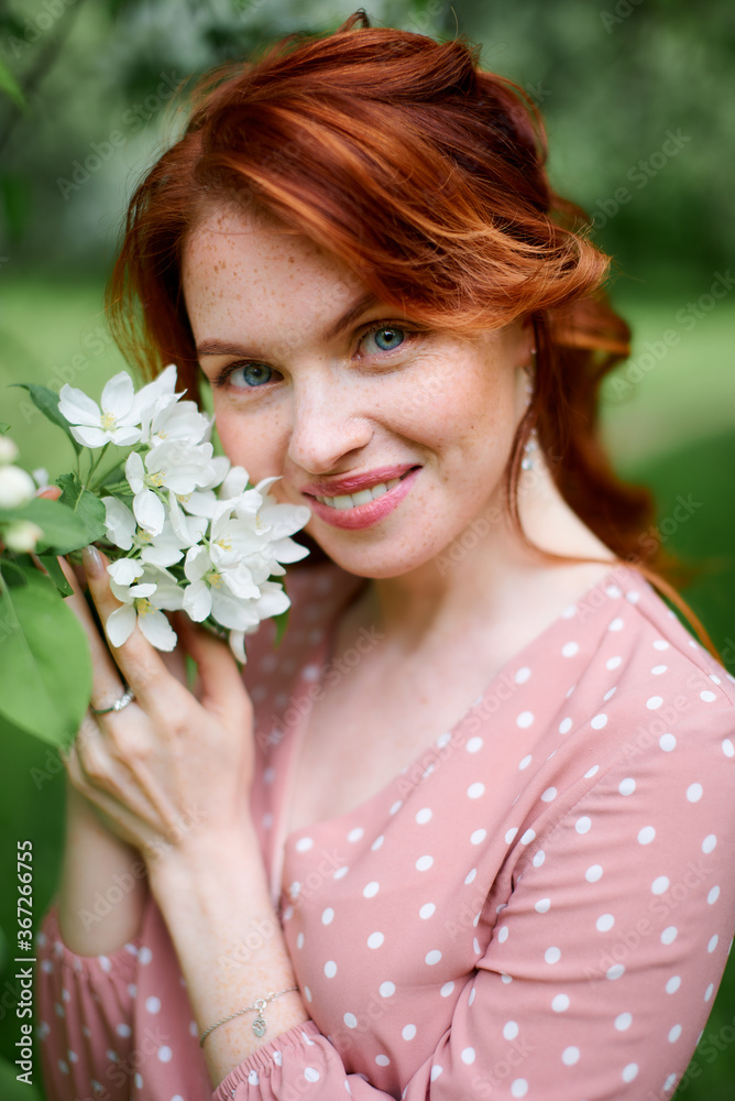 Naklejka premium Russian redheaded pretty girl in apple trees