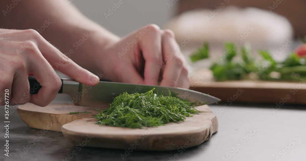 man chopping fresh dill on olive board side view man chopping fresh dill on olive board side view