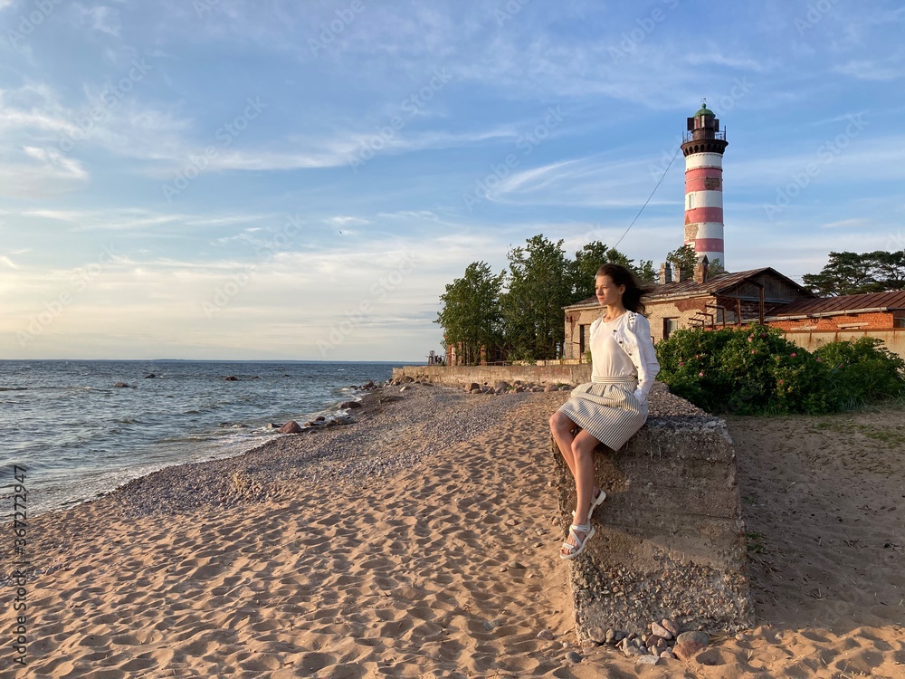 Young woman sitting on the background of a lighthouse
