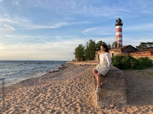 Obraz na płótnie Young woman sitting on the background of a lighthouse w salonie