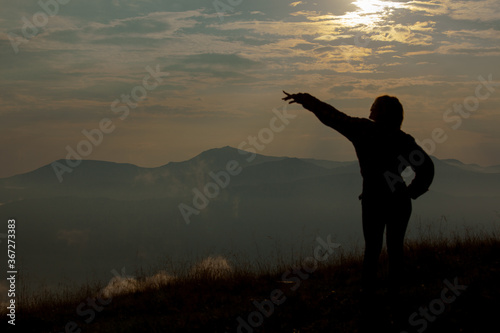 silhouette of a girl on a background of clouds sky in the mountains
