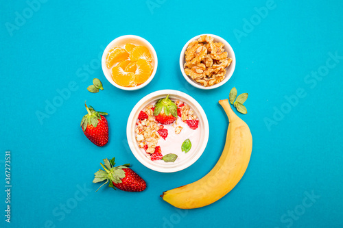 Healthy breakfast with granola and fruits, in white bowls, with a light blue background. 