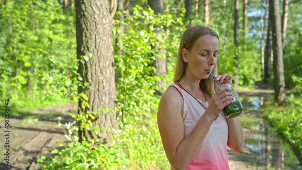 Sporty blonde woman in the park drinking smoothie Sporty blonde woman in the park drinking smoothie