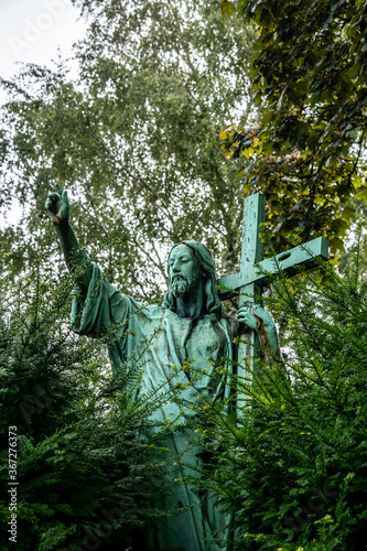 große Jesusfigur mit Kreuz inmitten eines Strauches