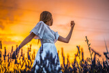 A young blonde Caucasian woman in a white dress in a cultivated lavender field in Navarra, Spain. lifestyle, rural lifestyle. Enjoying the countryside on a sunset