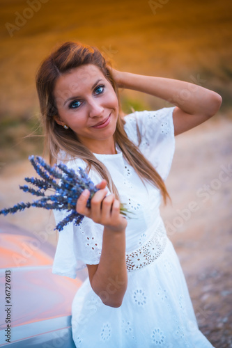 A young blonde Caucasian woman in a white dress in a lavender field. In a field of cultivation of the lavender product in Navarra, Spain. With pretty flowers