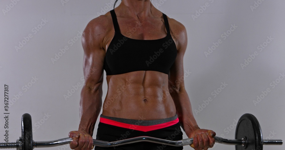 Muscular woman is lifting barbells for workout biceps. Bodybuilding. Muscular woman is lifting barbells for workout biceps. Bodybuilding.