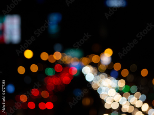 Abstract bokeh night light background, blurred lights traces from cars on road, defocused city traffic on street at night © Stella