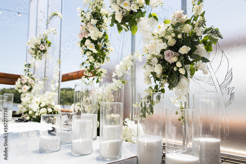 Close up of wedding ceremony with white transparent screens and fresh white flowers and candles