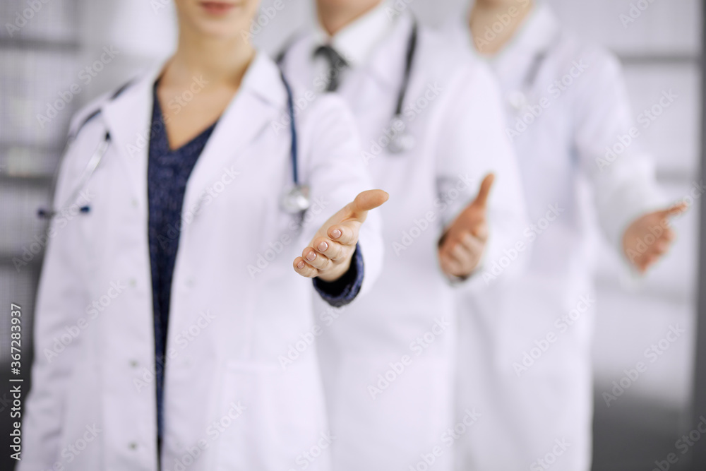 Doctors standing as a team while offering helping hand for shaking hand or saving life in clinic Doctors standing as a team while offering helping hand for shaking hand or saving life in clinic