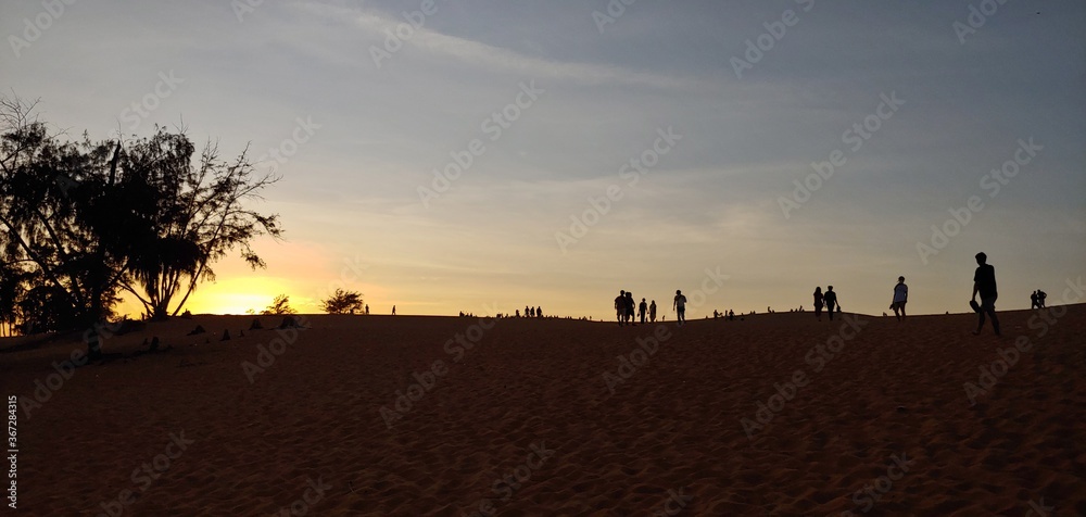 the desert of Vietnam. silhouette of sand mountains and sunset people