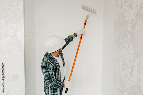 Builder repairman paints the wall with a roller