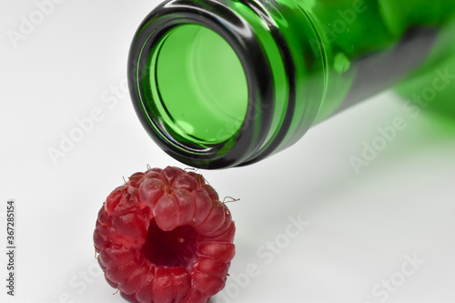Czerwone maliny i porzeczki z zieloną butelką.