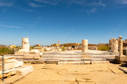 Ruins of an ancient city with stones, columns and temples on DELOS Island - mythological, historical, and archaeological site in Greece with blue sky background.