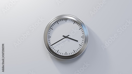Glossy chrome clock on a white wall at twenty to four. Time is 03:40 or 15:40