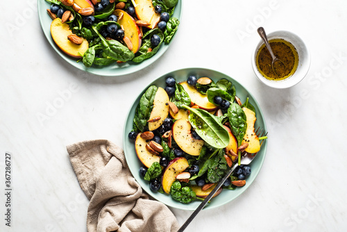 Baby spinach salad with peaches, blueberries and roasted almonds. Vegan dish. 