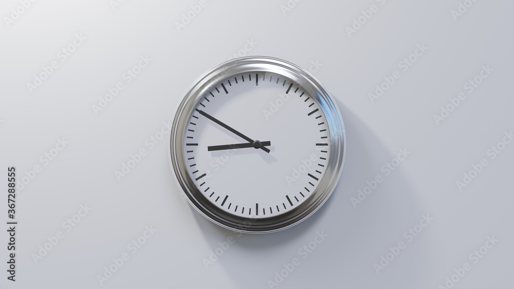 Glossy chrome clock on a white wall at ten to nine. Time is 08:50 or 20:50