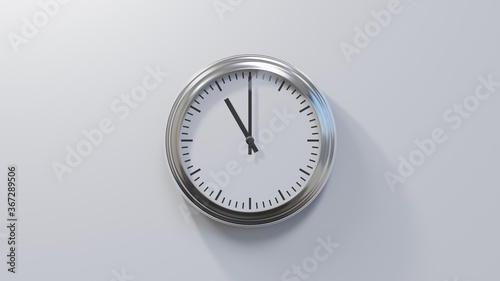 Glossy chrome clock on a white wall at eleven o'clock. Time is 11:00 or 23:00