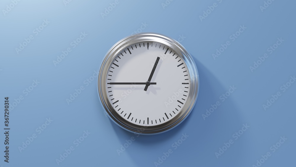 Glossy chrome clock on a blue wall at quarter to one. Time is 00:45 or 12:45