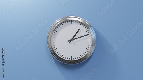 Glossy chrome clock on a blue wall at twelve past one. Time is 01:12 or 13:12