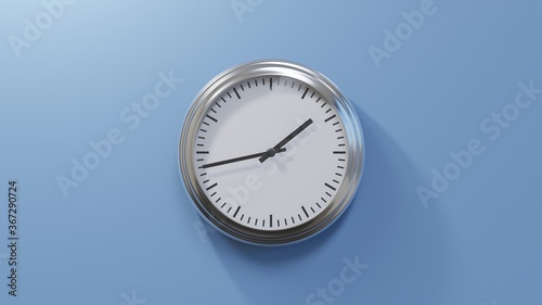 Glossy chrome clock on a blue wall at forty-three past one. Time is 01:43 or 13:43 photo