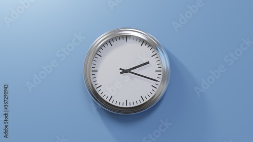 Glossy chrome clock on a blue wall at eighteen past two. Time is 02:18 or 14:18