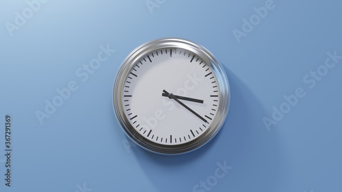 Glossy chrome clock on a blue wall at twenty-one past three. Time is 03:21 or 15:21