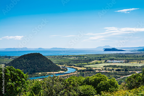 Aerial vew over a curve of Tongariro river and Lake Taupo with magnificent mountains in the background.