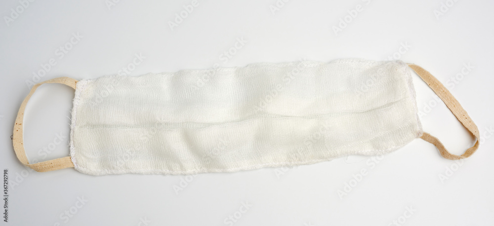 Obraz premium reusable mask of white cotton gauze on a white background, homemade remedy for viral diseases