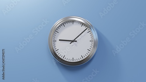 Glossy chrome clock on a blue wall at eight past nine. Time is 09:08 or 21:08