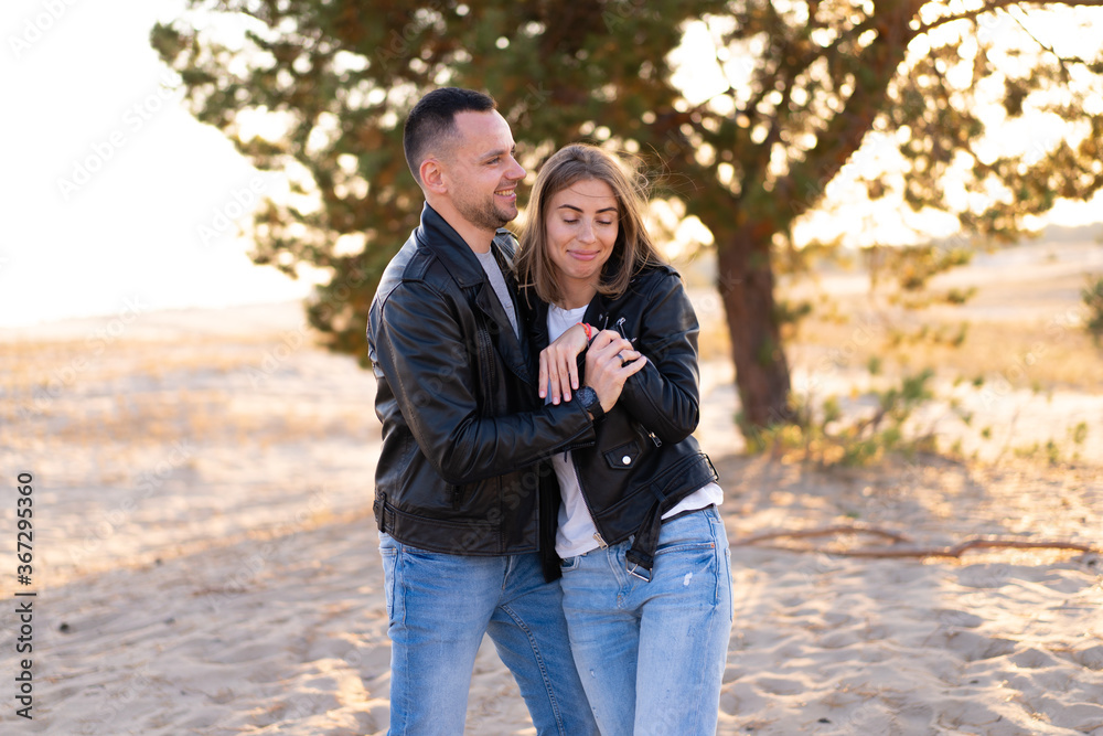 Happy and cute adorable adult couple of millennial hipsters, man with woman girlfriend walking, have fun play, laugh,smile and jump on sunset at desert Happy and cute adorable adult couple of millennial hipsters, man with woman girlfriend walking, have fun play, laugh,smile and jump on sunset at desert