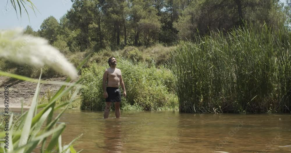 Man in a swimsuit in a river raises his arms Man in a swimsuit in a river raises his arms