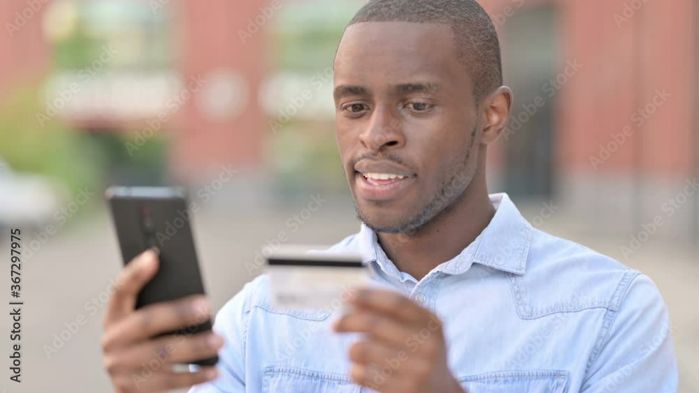 Outdoor Portrait of African Man making Online Payment on Smartphone Outdoor Portrait of African Man making Online Payment on Smartphone