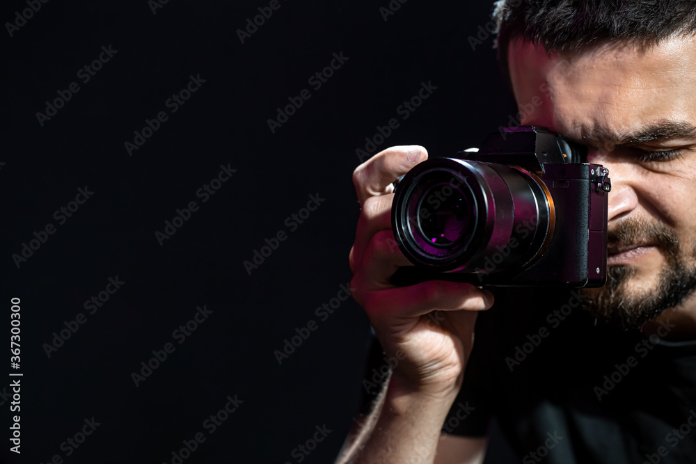 The person is holding a camera and is set up for shooting. The photographer looks into the camera's viewfinder and takes pictures. Object on a black background.