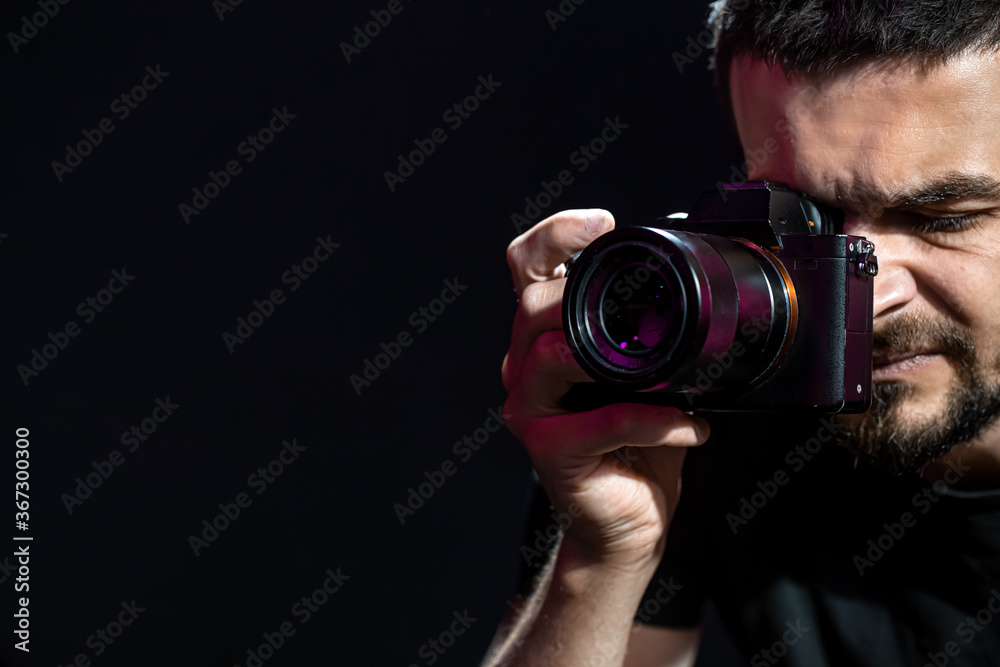 The person is holding a camera and is set up for shooting. The photographer looks into the camera's viewfinder and takes pictures. Object on a black background. The person is holding a camera and is set up for shooting. The photographer looks into the camera's viewfinder and takes pictures. Object on a black background.