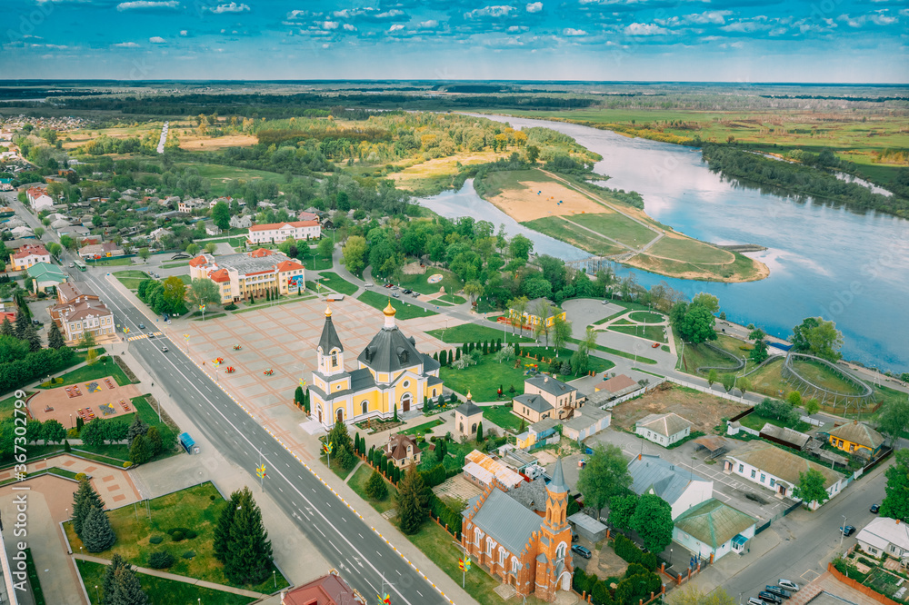Fototapeta premium Rechytsa, Belarus. Aerial View Of Residential Houses, River Dnieper And Holy Assumption Cathedral In Sunny Summer Day. Top View. Drone View. Bird's Eye View