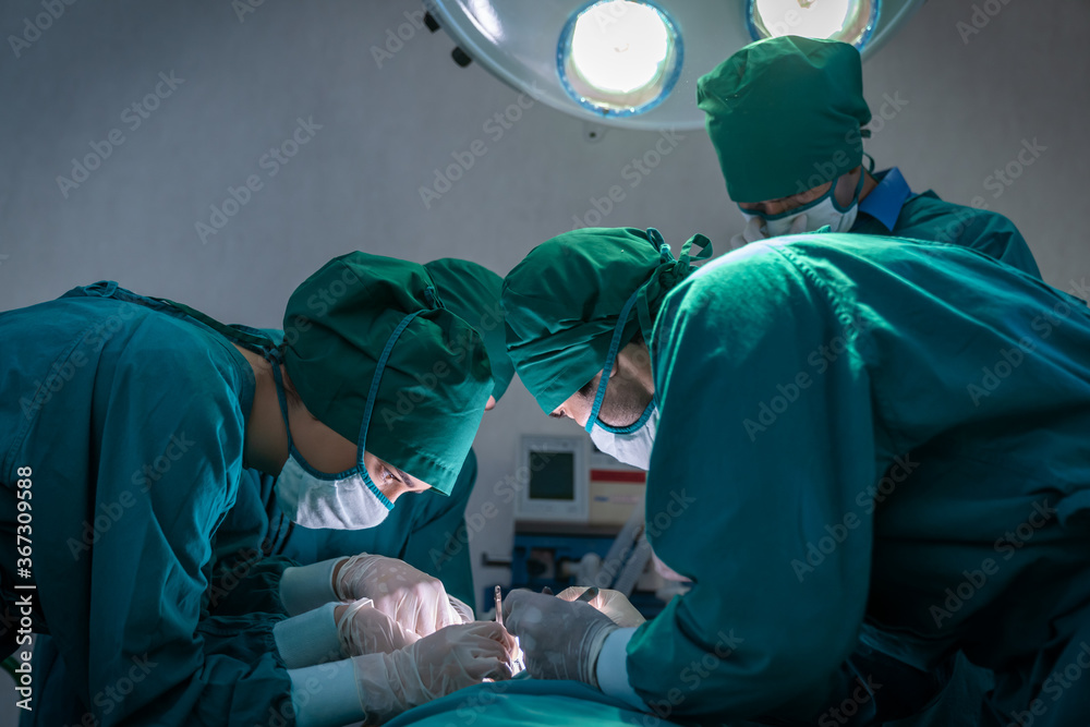 Medical team in uniform wearing face mask and gloves doing surgery with medical tools in operation room at hospital. Medical team in uniform wearing face mask and gloves doing surgery with medical tools in operation room at hospital.