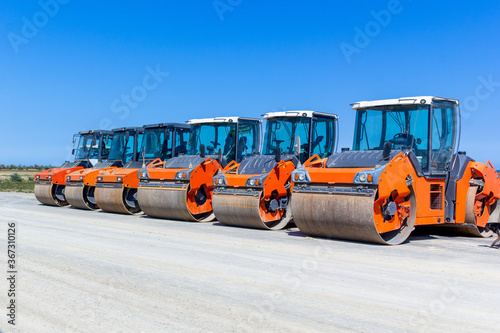 Asphalt road-rollers on parking lot. ..Red road rollers parked on the unfinished road construction site