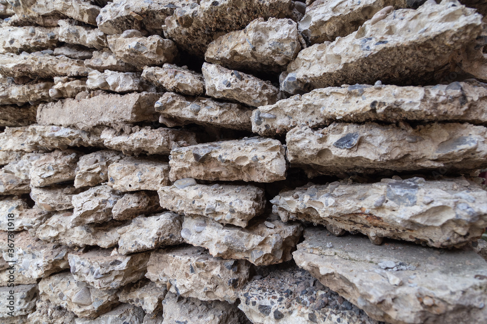Broken rough pieces of an old textured concrete stacked together. Recycling and reuse crushed concrete rubble, building material, blocks. Crushed concrete Background. Road repair, replacement Broken rough pieces of an old textured concrete stacked together. Recycling and reuse crushed concrete rubble, building material, blocks. Crushed concrete Background. Road repair, replacement