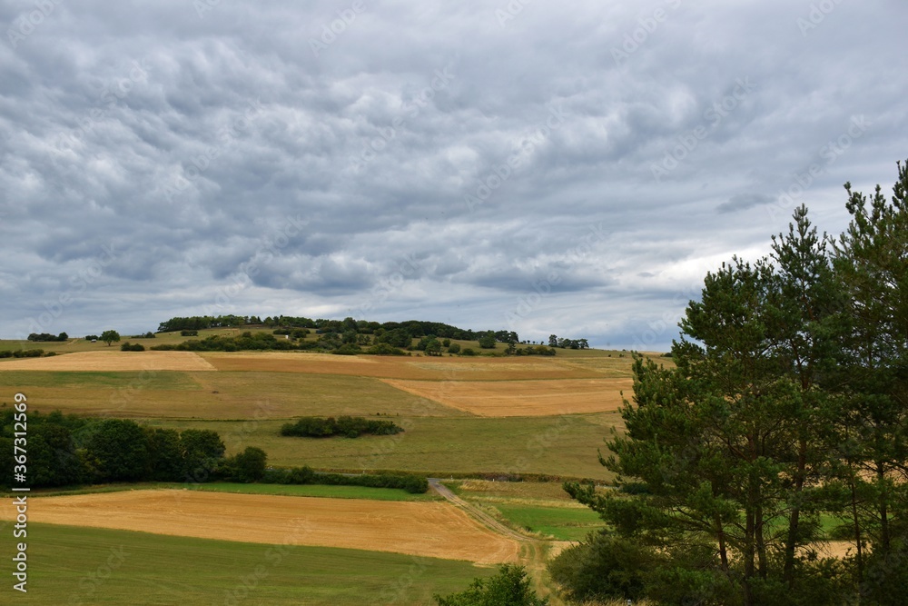 Dramatic cloudscape over colorful landscape with fields and meadows in Eifel mountains, Germany Dramatic cloudscape over colorful landscape with fields and meadows in Eifel mountains, Germany