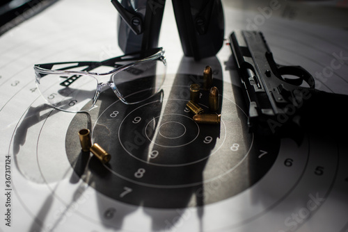 Shooting target with ammunition, pistol, ballistic glasses and headphones
